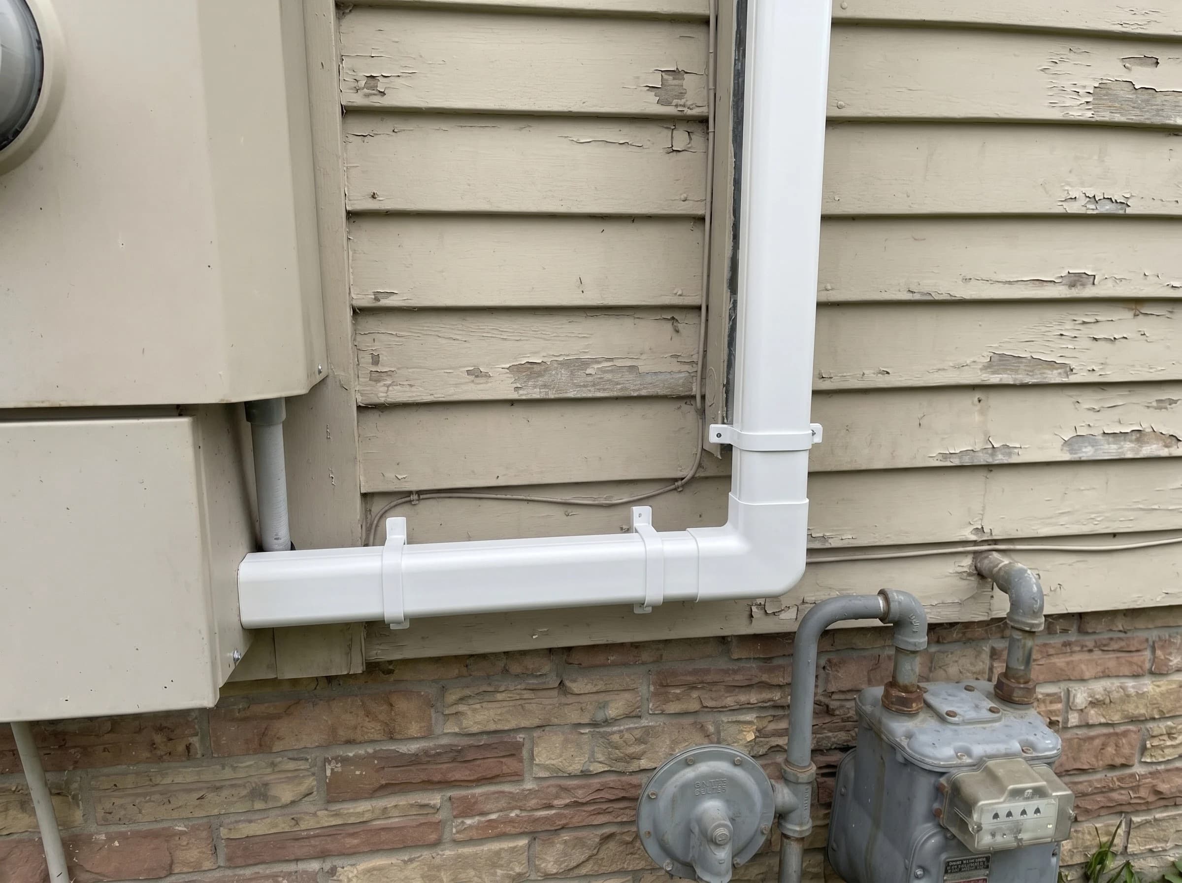 Clean refrigerant line install on a residential exterior wall — straight copper run hidden in a white line-set cover with seamless joints